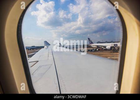 Blick aus dem Flugzeugfenster auf weißen Flügel und PARKPLATZ und American Airlines Jets im Hintergrund. Miami. USA. Stockfoto