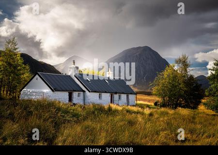 Ein atmosphärisches HDR-Bild von Blackrock Cottage am Kopf von Glen Coe mit Regen und Sonnenschein über Buachaille Etive Mor. Schottland. 28. September 2025 Stockfoto