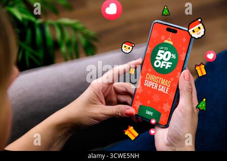 Weihnachtsangebot. Frau mit einem Handy und einer Verkaufsanzeige und vielen Emojis um sie herum. Marketing, Werbung für Weihnachtsrabatte, Internet Stockfoto