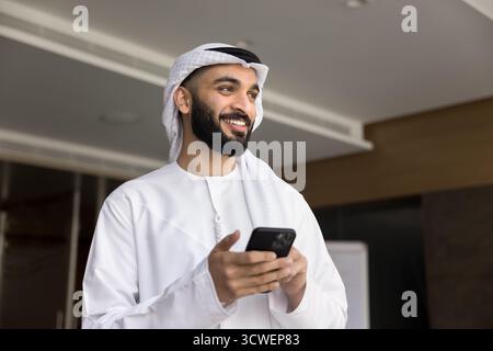 Glücklicher erfolgreicher arabischer Geschäftsmann mit Handy Stockfoto