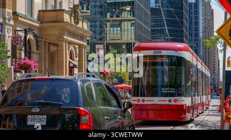Toronto ON, Kanada - 4. Juli 2022: Die Bombardier-Straßenbahn fährt durch die Innenstadt von Toronto, flankiert von Wolkenkratzern und lebhaften Straßenszenen, Highlighti Stockfoto