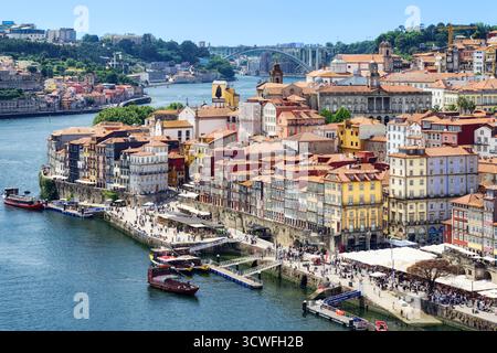 Porto, Portugal, 14. Juni 2025: Panoramablick auf die farbenfrohen Häuser von Portos Stadtteil Ribeira entlang des Flusses Douro mit der Ponte da Arrábida Bride Stockfoto