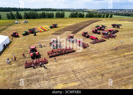 Traktor, der an sonnigen Tagen auf dem Feld arbeitet. Arbeitsbegriff in der Ackerbau- und Landwirtschaftsindustrie. Das Land mit dem Pflug mit einem Traktor pflügen. harv Stockfoto
