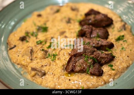 Risotto mit Fleischscheiben, serviert auf Teller. Es ist ein beliebtes italienisches Reisgericht. Stockfoto