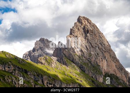 Dramatischer Gipfel von Gran Fermeda und Sass Rigais, der sich in Gröden in den italienischen Dolomiten scharf gegen einen teilweise bewölkten Himmel erhebt Stockfoto