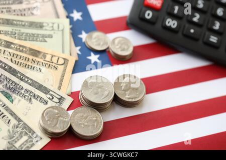 US-Dollar-Geldscheine und Taschenrechner auf amerikanischer Flagge Nahaufnahme. Geldinvestitionskonzept und Steuerzahlung Stockfoto