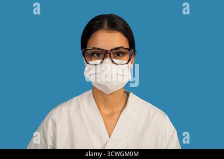 Medizinisches Fachpersonal trägt Schutzmaske und Brille auf blauem Hintergrund Stockfoto