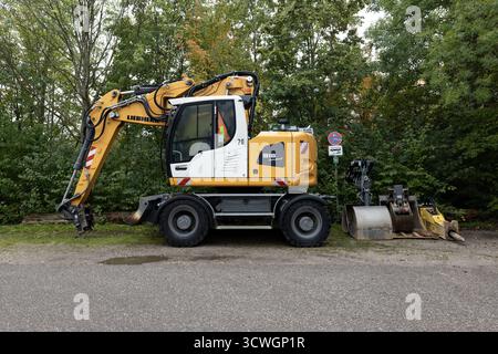 Bagger mit mehreren auswechselbaren Werkzeugen auf dem Parkplatz Hirschgarten im Westen der Stadt München Stockfoto