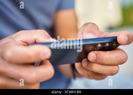 Mann mit Smartphone, Nahaufnahme. Männliche Hände halten das Smartphone und spielen im Freien mobile Spiele. Konzept von Technologie, digitalem Entertainment und gadge Stockfoto