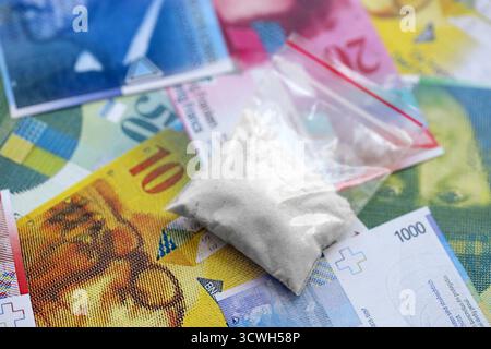 Schweizer Franken-Banknoten und Kokainpackung. Die aktuellen Francs-Geldrechnungen und Suchtstoffe liegen in großer Menge auf dem Tisch. Das Konzept des Drogenhandels in der Schweiz Stockfoto
