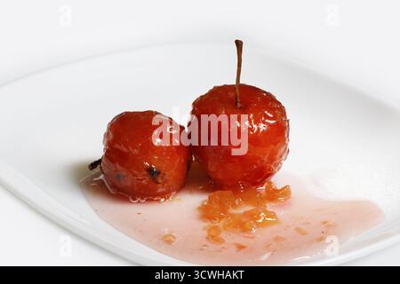Rote Äpfel in rose Sirup mit kleinen Stücken von Zucchini in isolierten weißen Hintergrund Stockfoto