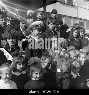 Der gefeierte sowjetische Eisbrecherkapitän Anatoly Lamekhov, ein Held der Sowjetunion, posierte in den 1980er Jahren für ein Gruppenfoto mit Schülern und Lehrern an einer Schule in seiner Heimatstadt Sloviansk, der ukrainischen SSR Der dekorierte Polarforscher ist Ehrengast bei einer festlichen Schulversammlung. Kinder jeden Alters in Schuluniformen versammeln sich um den lokalen Helden auf den Stufen des modernistischen Schulgebäudes. Dieses Bild fängt einen Schlüsselmoment der patriotischen Erziehung und des Stolzes der Gemeinschaft ein Stockfoto