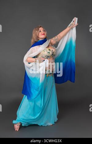 Erwachsene Frau mittleren Alters Bauchtänzerin kleidet sich in Tanzbühne Kostüm - BH Top und blauer langer Rock mit Pareo und sie trägt keine Schuhe, p Stockfoto