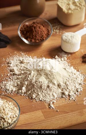 Molkenproteinpulver, gemahlene Haferflocken, Nussbutter und Kakao - Zutaten für hausgemachte Eiweißschokolade auf einem Tisch Stockfoto