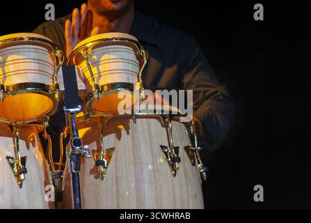 Conga und Bongo setzen Schlaginstrumente, afrikanischer Mann klopft mit den Händen, spielt Schlagzeug, Musik auf der Bühne Stockfoto