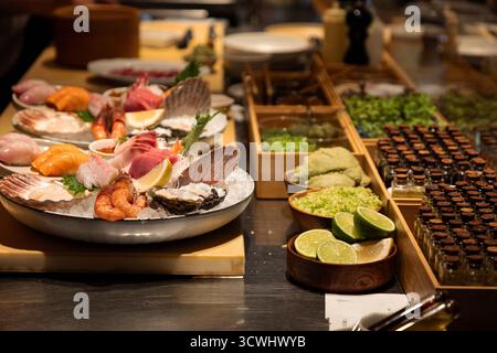 Auf der Platte mit frischen Meeresfrüchten werden verschiedene Muscheln und Fische präsentiert, die wunderschön mit Garnituren und Gewürzen angeordnet sind, um eine appetitliche Präsentation zu schaffen Stockfoto