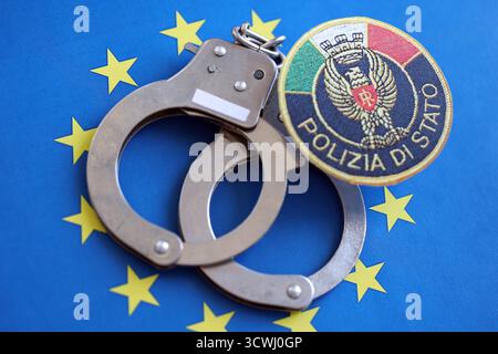 KIEW, UKRAINE - 6. SEPTEMBER 2025 Flicken der italienischen Staatspolizei und Handschellen auf blauer Flagge der Europäischen Union Nahaufnahme Stockfoto