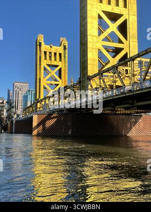 Der hohe Anker der Tower Bridge in Sacramento erhebt sich über den Sacramento River und spiegelt sich im Wasser nahe der Skyline der Stadt wider Stockfoto