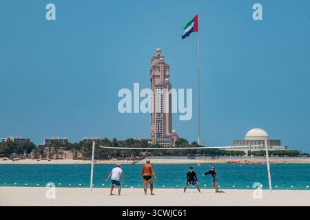 Leute spielen Volleyball an einem Sandstrand in Abu Dhabi. Corniche Beachfront mit Blick auf Marina Mall und Rixos Marina Hotel Abu Dhabi VAE. Reise-Pho Stockfoto
