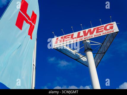 Hellweg Baumarkt Eisenwarenladen Werbetafel und Flagge in Berlin, Deutschland, an einem sonnigen Tag mit blauem Himmel und weißen Wolken Stockfoto