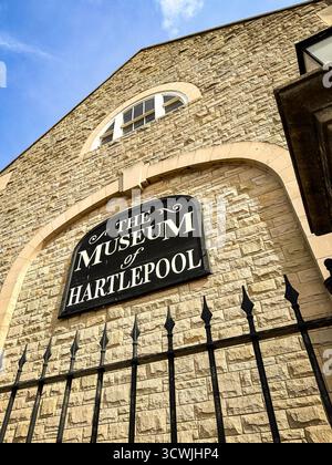 Blick auf das Museum of Hartlepool mit Bogenfenstern, Ziegelfassade und einem schmiedeeisernen Zaun unter klarem, blauem Himmel Stockfoto