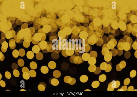 Abstrakte gelbe Bokeh-Lichter, strukturierter Hintergrund mit leuchtenden Kreisen auf dunklem Hintergrund. Verschwommene Lichtkreise, festliche Feiertagstextur für DE Stockfoto