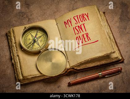 Meine Geschichte ist noch nicht vorbei - positive Affirmation Note. Handschrift in einer Zeitschrift mit Messingkompass, Geschäfts-, Karriere- und Persönlichkeitskonzept. Stockfoto