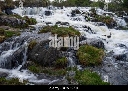 Wasserfall, der über moosbedeckte Felsen in der Landschaft des Lake District fließt Stockfoto