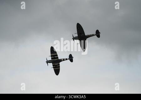 Zwei Supermarine Spitfire fliegen in Formation gegen bewölkten Himmel auf der Duxford Airshow Stockfoto