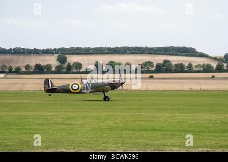 Supermarine Spitfire Kampfflugzeug auf dem Grasflugplatz mit landschaftlicher Kulisse Stockfoto