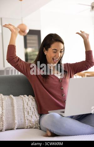 Fröhlich überfröhliche junge Lateinfrau, die nach Freude am Laptop schreit Stockfoto