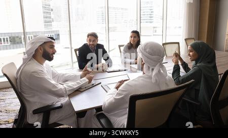 Ein selbstbewusster arabischer Geschäftsmann versammelt multiethnische Mitarbeiter zur Besprechung im Sitzungssaal Stockfoto