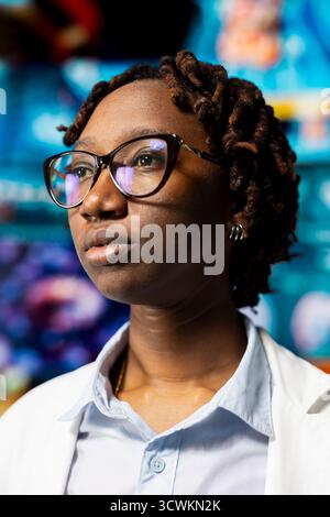 Nahaufnahme einer Ärztin, die interaktive Dashboards mit medizinischen Forschungsdaten und 3D-Anatomiemodellen überwacht. afroamerikanischer Kliniker, der neben einer multimedialen Wand steht und futuristisches medizinisches Bild zeigt Stockfoto