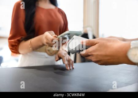 Zugeschnittene Aufnahme eines Outlet-Kunden, der sein Smartphone am POS-Terminal hält Stockfoto