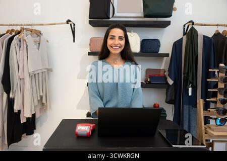 Fröhliche weibliche hispanische Ladenfrau posiert im Showroom Stockfoto
