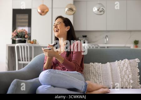 Aufgeregt glücklich hispanische Frau, die Smartphone hält und lacht Stockfoto