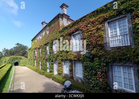 Diese malerische Aussicht zeigt das charmante Herrenhaus, umgeben von Efeu im Castrelos Park, Vigo, Spanien, und zeigt die Schönheit der Natur an einem sonnigen Tag. Stockfoto