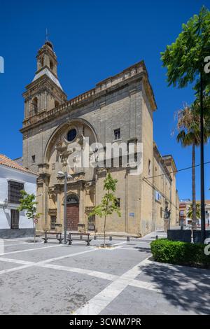 Besucher bewundern die historische Kirche von San Francisco in Sanlucar de Barrameda. Das barocke Design wird durch das helle Sonnenlicht und das klare Blau hervorgehoben Stockfoto