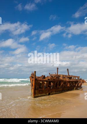 Die verrosteten Überreste des Schiffswracks der SS Maheno am Strand von K'gari, Australien. Die Metallstruktur ragt aus dem Sand in der Nähe des Wasserrandes hervor Stockfoto
