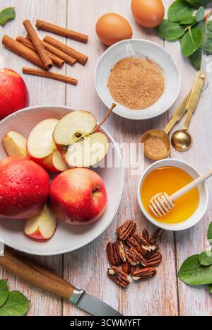 Frische rote Äpfel, Honig, Zimt und Zucker bereiten sich auf ein Herbstrezept vor Stockfoto