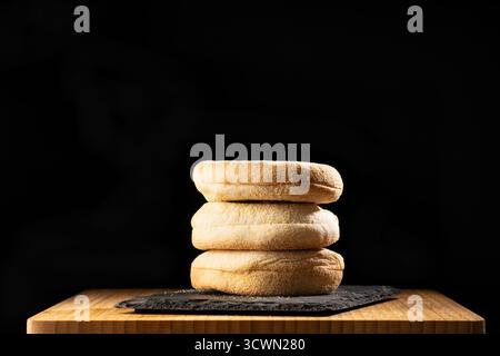 Nahaufnahme von frisch gebackenen Burgerbrötchen auf einer Holzoberfläche mit dunklem Hintergrund, Backen oder Fast Food. Stockfoto