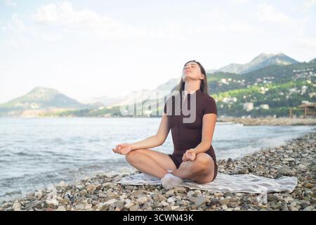 Junge Frau, die Yoga an der Küste übt, Outdoor-Fitness und aktiven Lebensstil genießt frische Luft Stockfoto