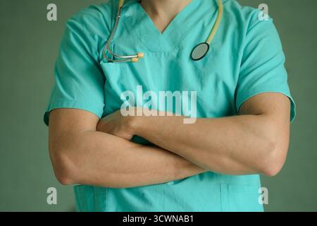 Porträt eines männlichen Arztes in Schutzmaske mit Stethoskop, Arme überkreuzt auf der Brust. Fokus auf Professionalität, medizinisches Personal und Krankenhausgesundheitskonzept in Nahaufnahme. Stockfoto