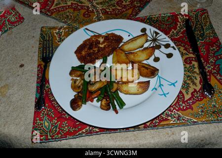 Hühnerschnitzel, gebratenes Gemüse und gebratene Kartoffelchips serviert und verzehrfertig. Stockfoto