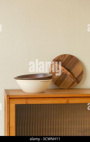 Elegante Keramikschale und Holzabdeckung auf modernem Schrank, Holzschale und Holzteller auf dem Schrank im Wohnzimmer Stockfoto
