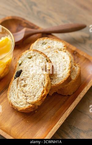 Geschnittenes Mehrkornbrot mit Samen und getrockneten Früchten auf Holztablett, Brot mit Rosinen und Honig auf Holzteller, Stockfoto Stockfoto