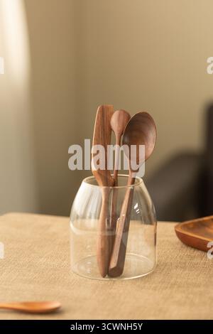 Löffel und Spatel aus natürlichem Holz im Klarsichthalter, Löffel aus Holz in einer Glasvase auf dem Tisch. Stockfoto