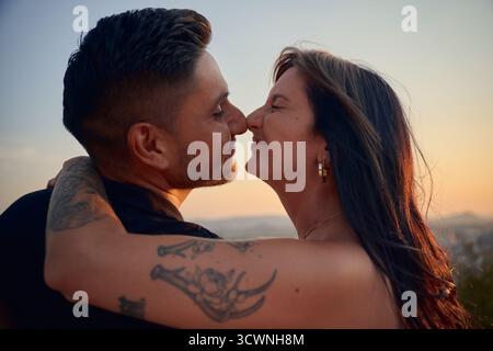 Glückliches junges Paar, das sich bei Sonnenuntergang mit der Nase küsst Stockfoto