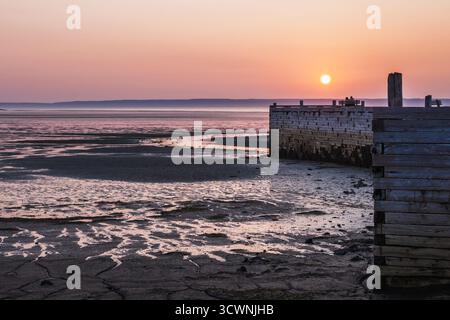 Sonnenuntergang bei Ebbe am Küstenpier, der von Paaren auf der Picknickbank genossen wird Stockfoto