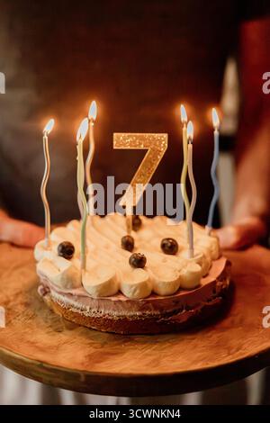 Geburtstagskuchen mit Kerzen und goldener Nummer sieben-Topper Stockfoto